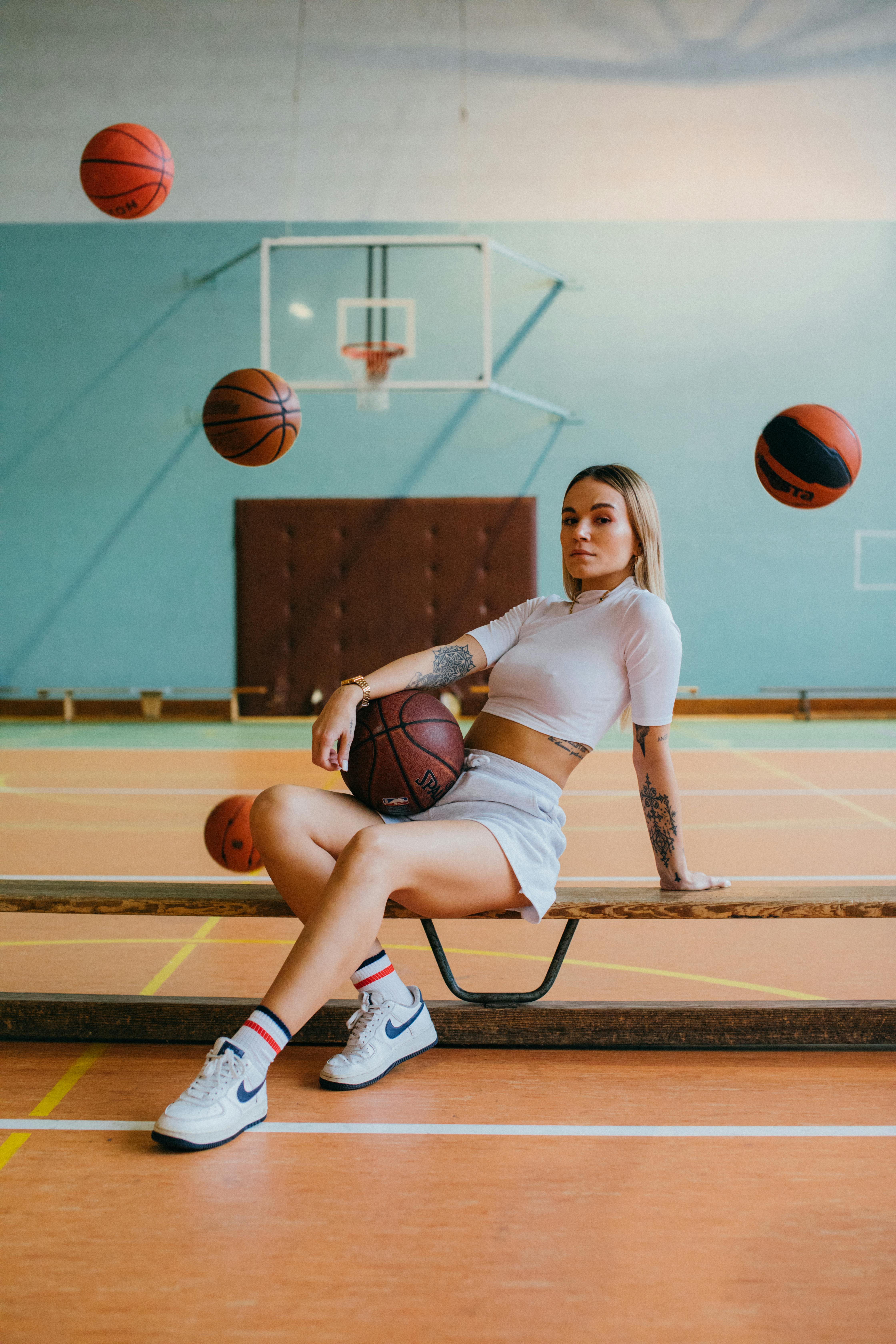 a woman in white crop top and white shorts sitting on brown wooden bench