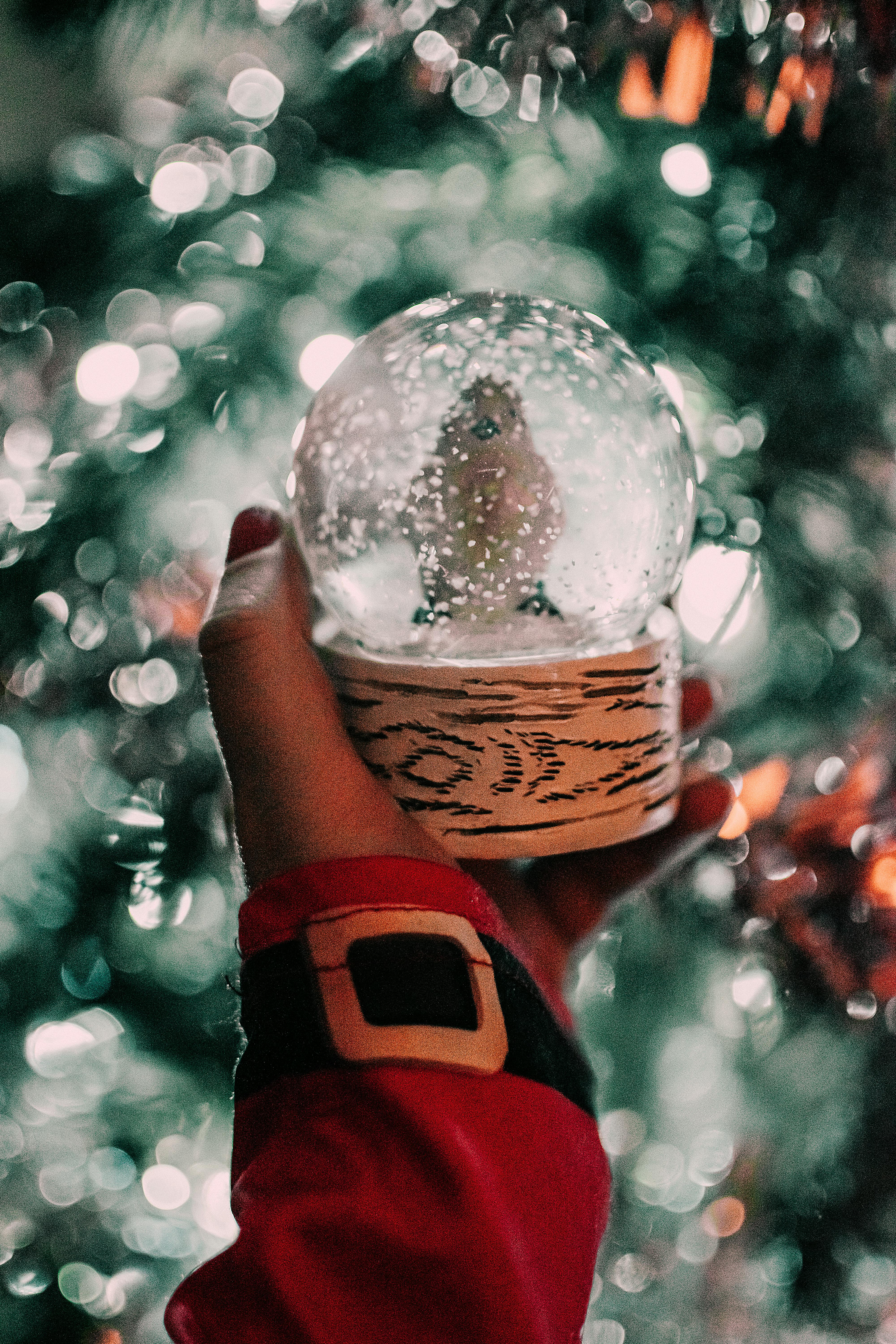 A festive snow globe held by a hand in a Santa suit captures holiday spirit.