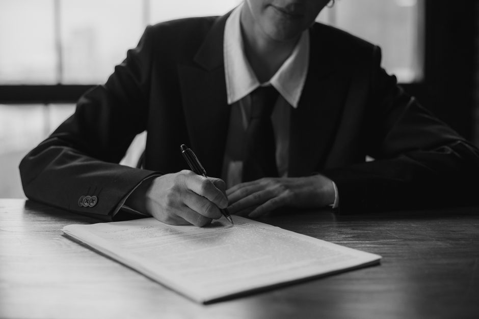 Foto en blanco y negro de un empresario escribiendo en un documento en interiores.