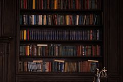 A sophisticated library scene featuring a leather sofa, bookshelves, and a statue of justice with a gavel on the table.