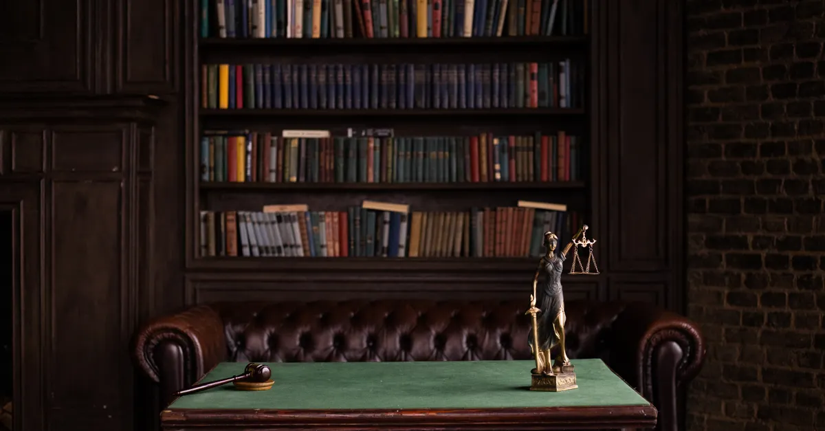 A study room with shelves of law books, a gavel and a Lady Justice statue