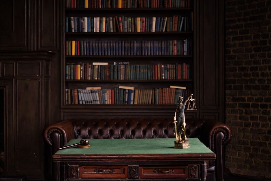 Gavel on a wooden desk beside the Lady Justice statue — the 1970 Controlled Substances Act classified ibogaine before any US clinical research had been conducted