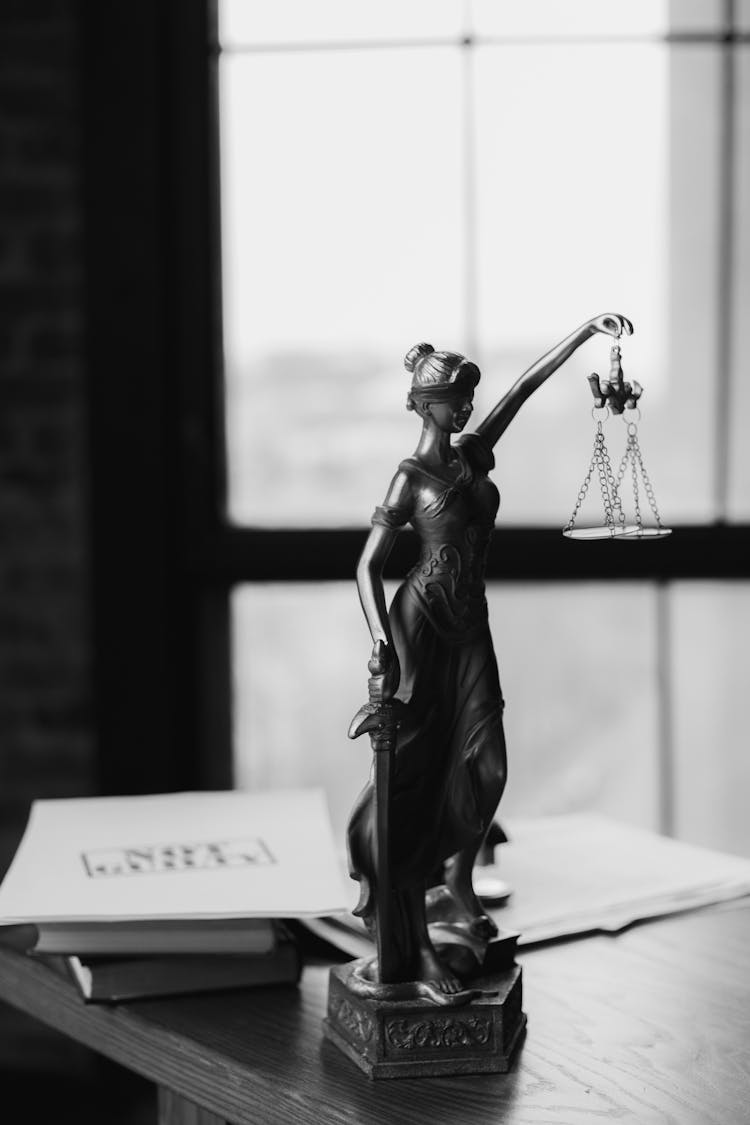 Grayscale Photo Of A Lady Justice Statue On Table