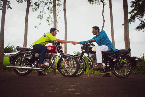 Free Two smiling motorcyclists shake hands while sitting on Royal Enfield bikes, showcasing camaraderie and adventure. Stock Photo