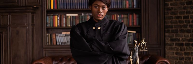 A confident female judge in a formal robe posing in a classic legal library setting.