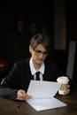 Woman in Black Blazer Reading While Holding a Disposable Cup