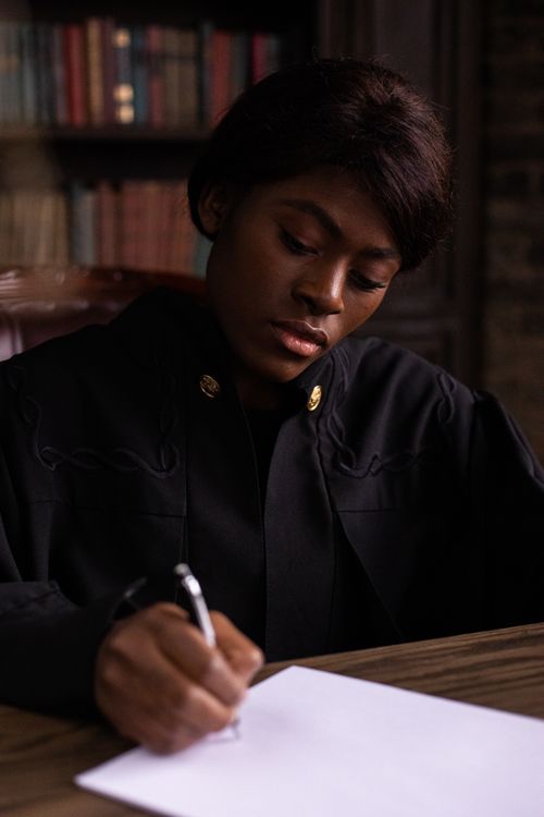 Free A woman deeply concentrating while writing at a desk in a library. Stock Photo
