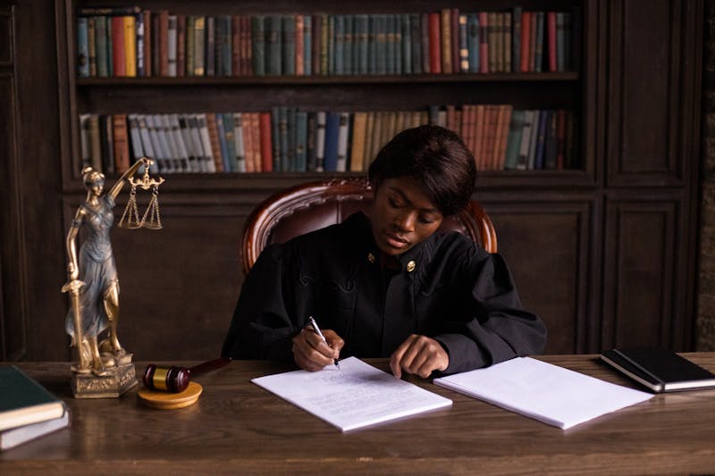Legal professional writing on documents at desk