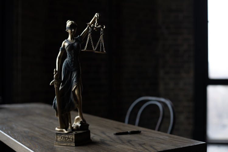 A Figurine Of The Lady Justice On A Table