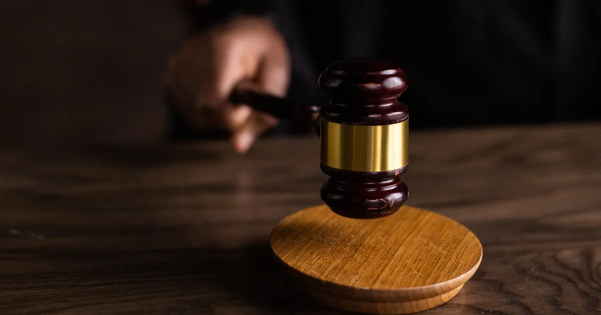 A judge's gavel striking its sound block on a dark wooden desk, representing careful legal review