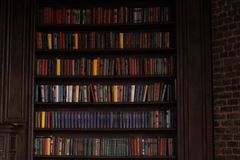 Black female judge reading papers at desk in office with bookshelves.