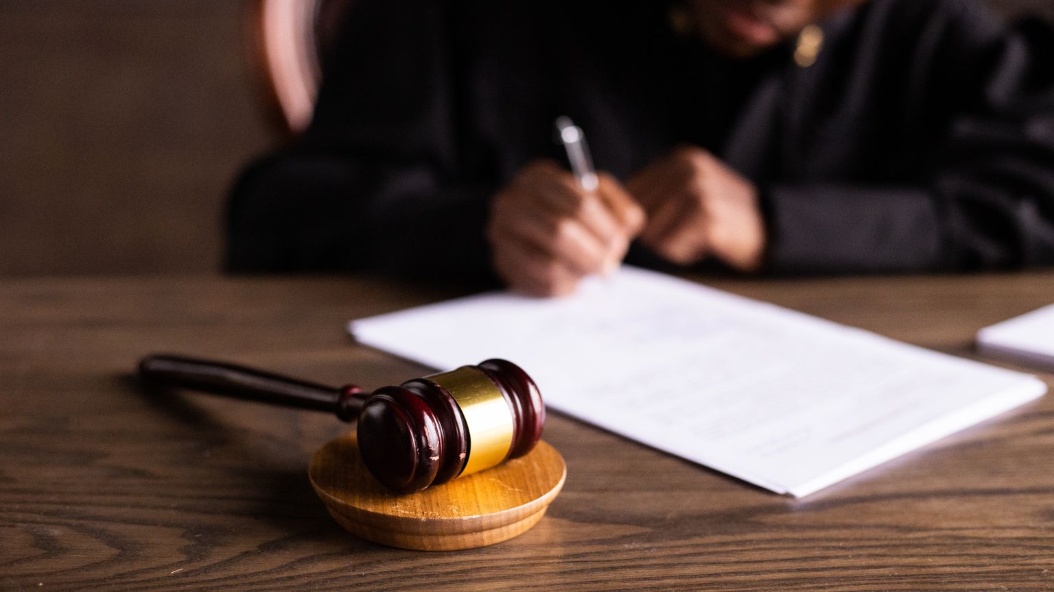 A judge signing court documents beside a gavel