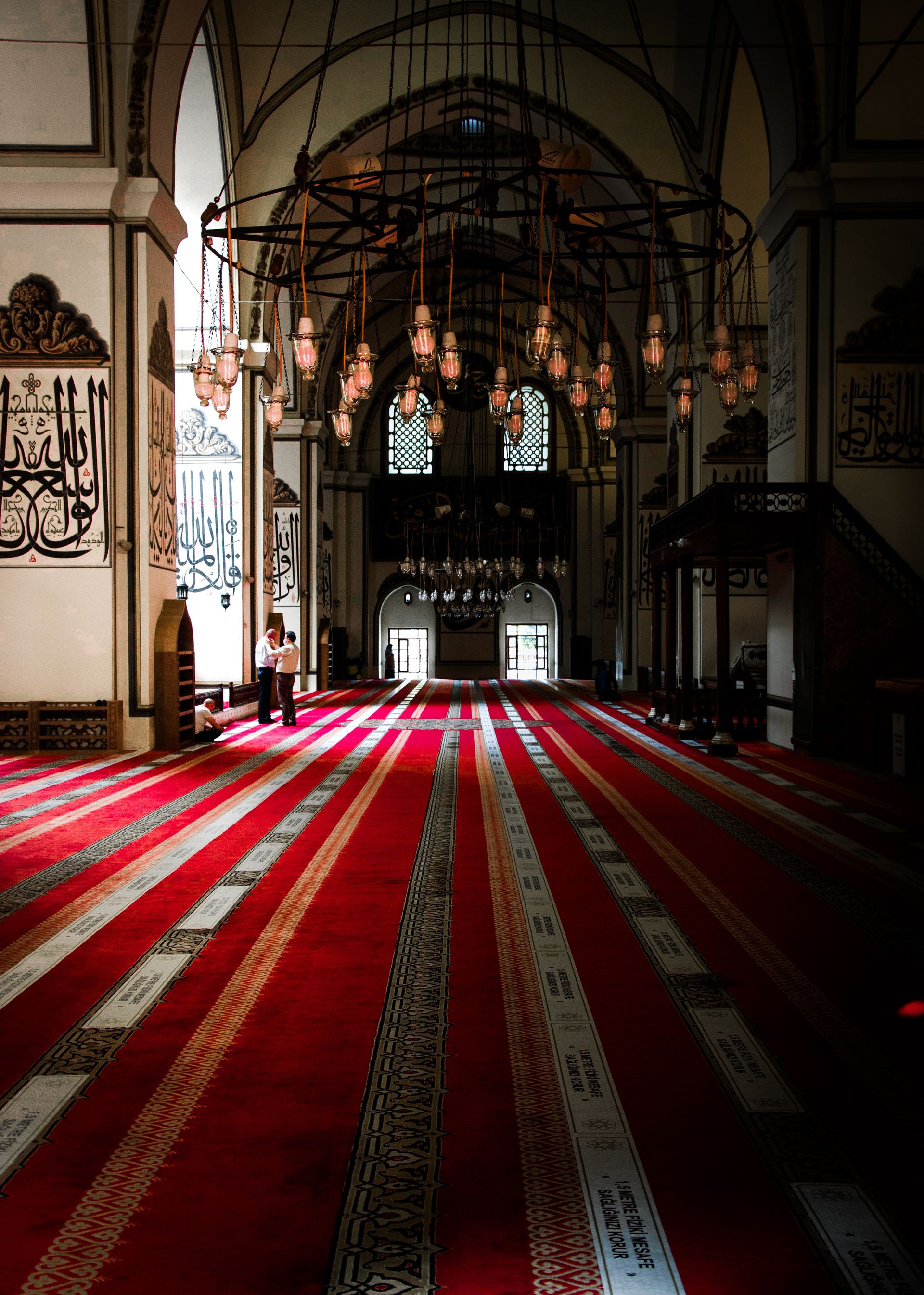 Beautiful interior of a mosque with vibrant red carpet and intricate chandeliers