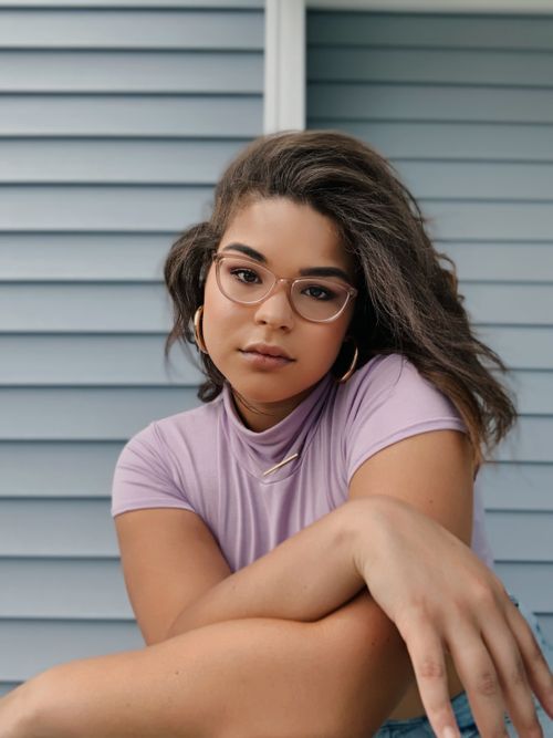 Free Confident woman with eyeglasses posing against blue siding background. Stock Photo