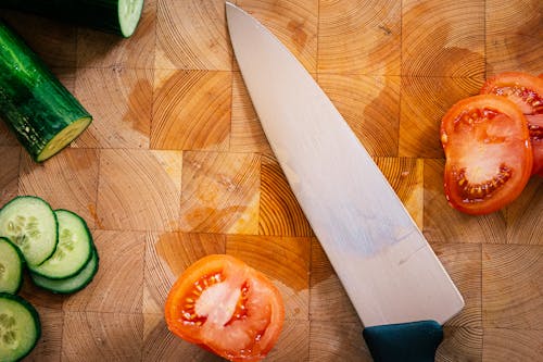 Close-Up Shot of Sliced Tomato and Cucumbers beside a Knife