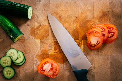 Close-Up Shot of a Knife and Sliced Vegetables on a Wooden Chopping Board
