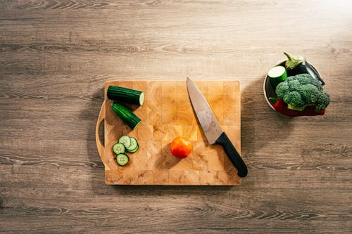 Close-Up Shot of a Knife and Sliced Vegetables on a Wooden Chopping Board