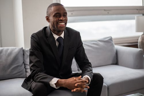 Free Happy Man in Black Suit Sitting on a Couch Stock Photo