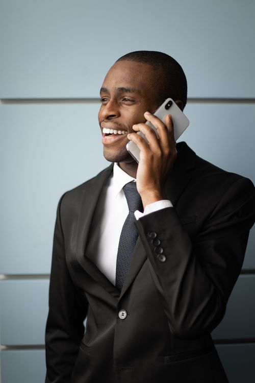 Free Confident African American businessman smiling while talking on phone in formal attire. Stock Photo