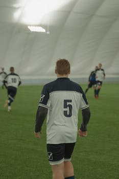 Back view of soccer players during an indoor game, focusing on number 5 jersey.
