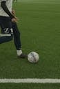 Person in Black and White Nike Soccer Jersey Kicking Soccer Ball on Green Grass Field during