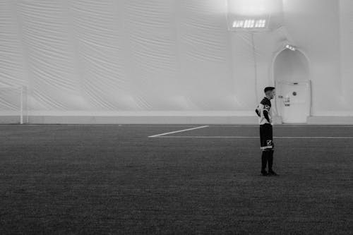 Grayscale Photo of Man in a Soccer Field
