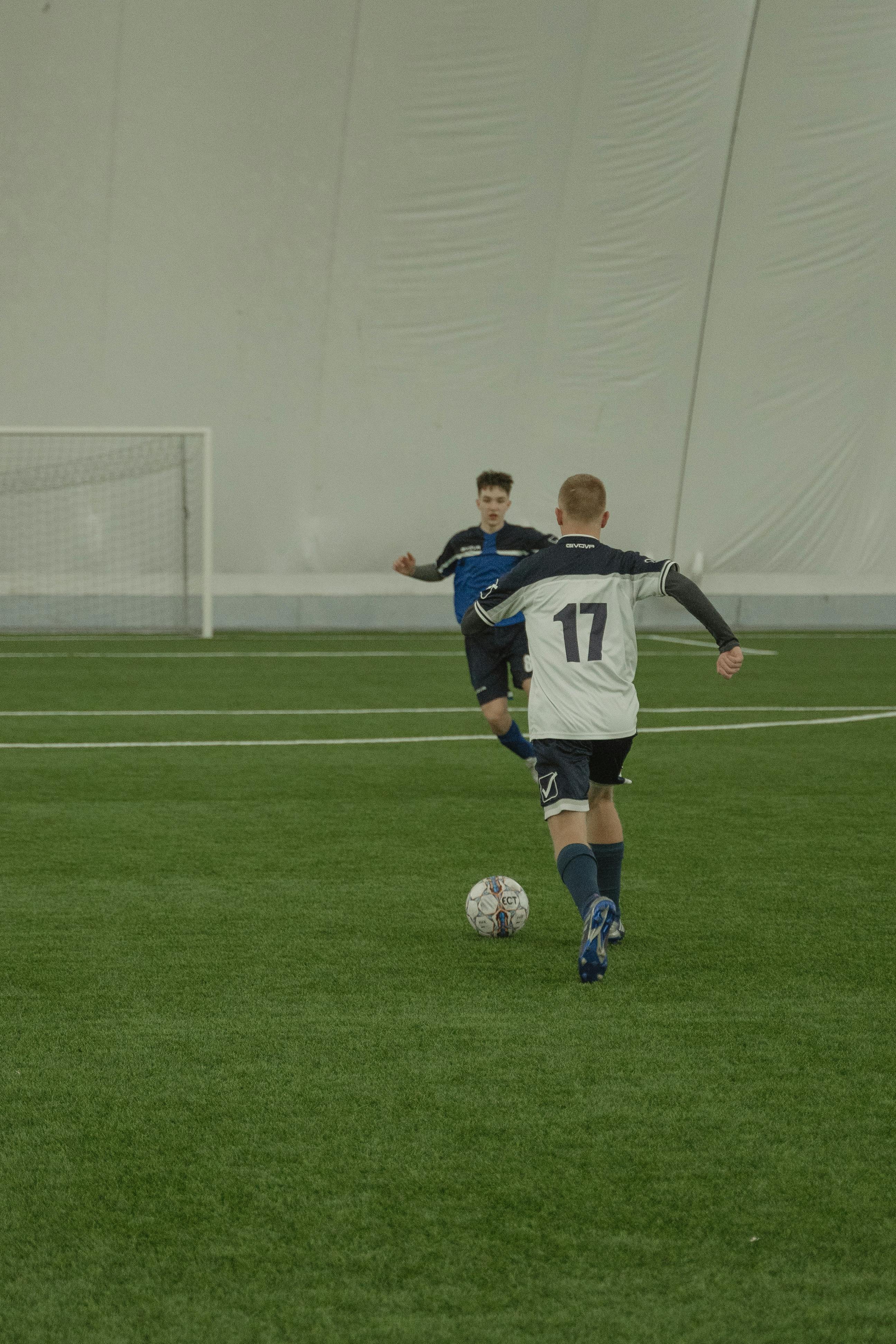 man in blue and white soccer jersey kicking soccer ball on green field