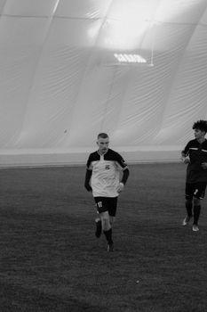 Black and white photo of soccer players running indoors during a match.