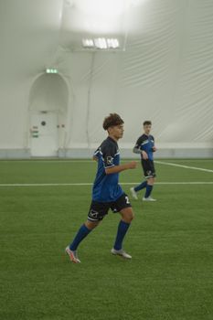 Young soccer players actively engaged in a game on an indoor field.