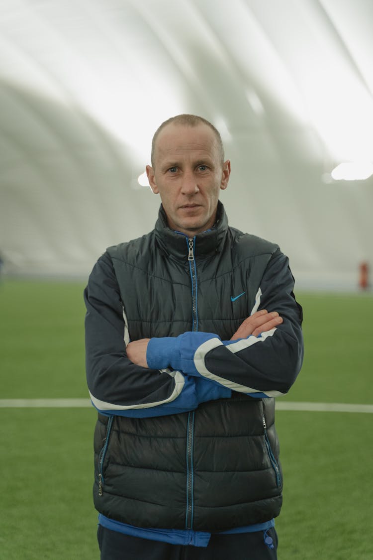 A Man Wearing A Puffer Jacket In A Stadium