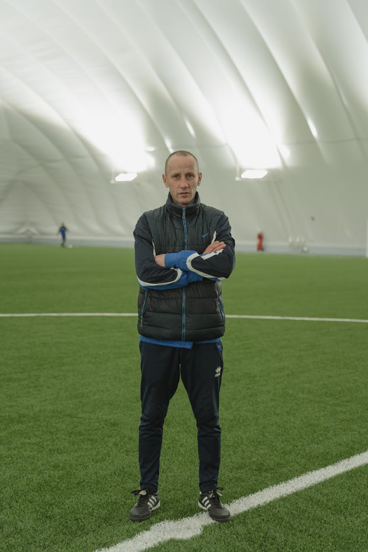 A Man Wearing A Puffer Jacket In A Stadium