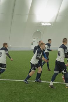 Young soccer team practicing indoors on artificial field, showcasing teamwork and athleticism.