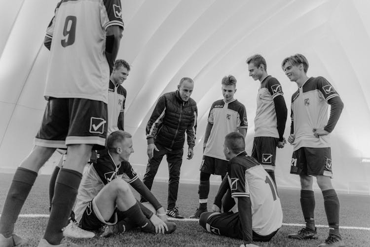 A Grayscale Of A Coach Talking To His Team