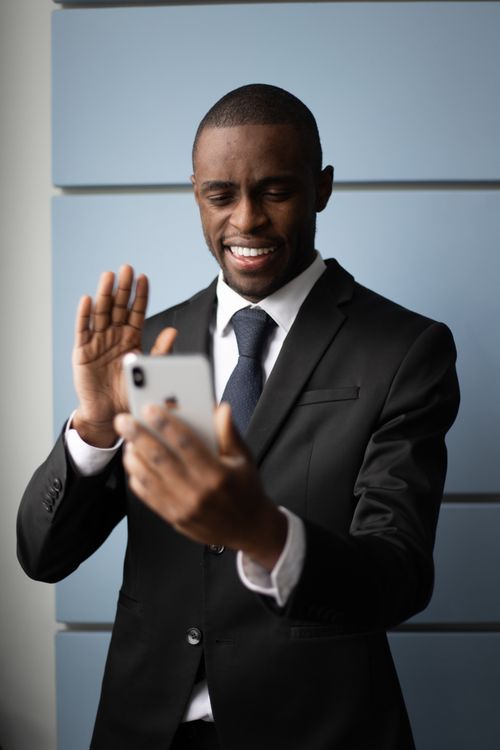 Free African American businessman in suit video calling with a smartphone indoors. Stock Photo