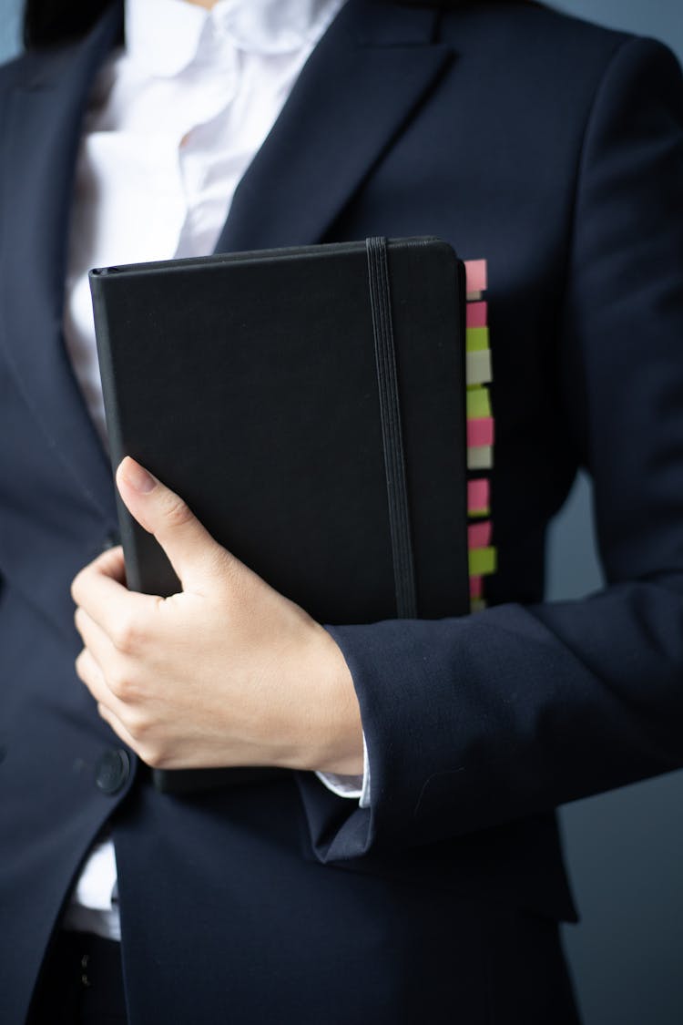 A Woman In A Suit Holding A Planner With Label Tabs