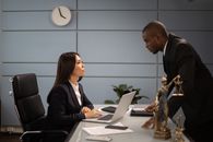Man in Black Suit Jacket Sitting Beside Woman in Black Blazer