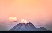 Majestic view of volcano emitting smoke against a pastel sunset in Yakushima, Japan.