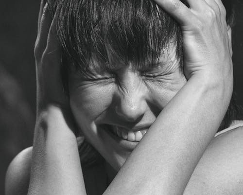 Grayscale Photo of Woman Holding Her Head With Pain