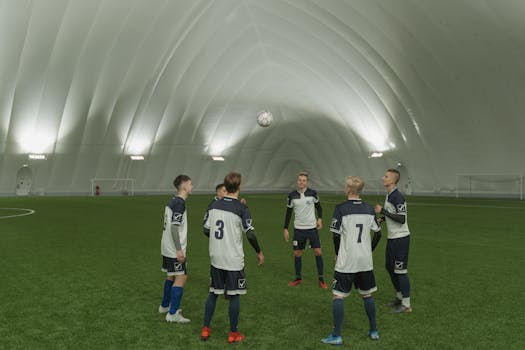 A soccer team practicing indoors, players in blue and white uniforms focusing on ball control.