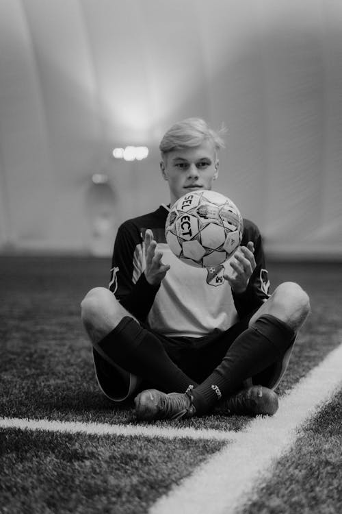 Grayscale Photo of Boy Holding a Soccer Ball