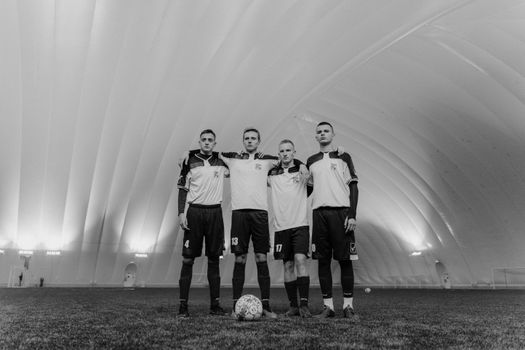 A grayscale group portrait of young male soccer players in an indoor dome.