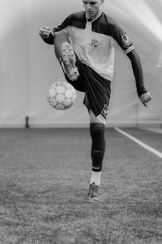 Dynamic grayscale photo of a soccer player in motion, skillfully controlling the ball during practice.