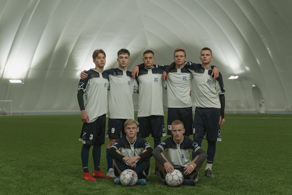 A group of young male soccer players in uniform posing on an indoor field.