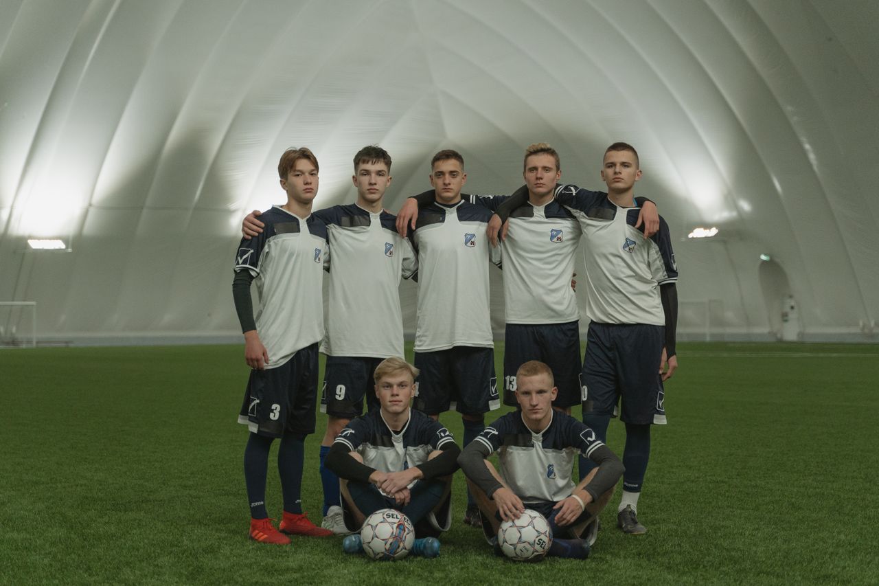 a group of young male soccer players in uniform posing on an indoor fi