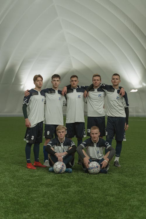 Group of Soccer Players Standing on Green Grass Field