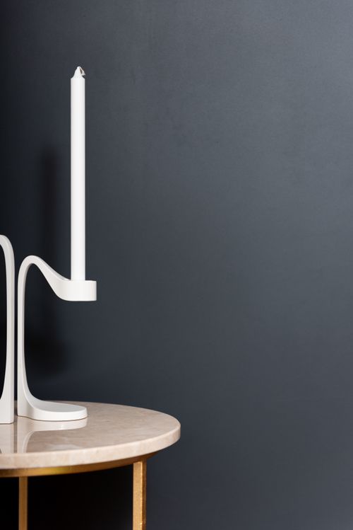 Free Element of white elegant candlestick placed on round marble side table with golden stand on black background in modern studio Stock Photo