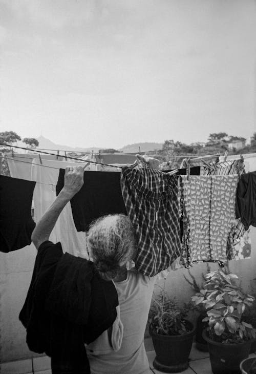 A Grayscale of a Woman Hanging Clothes