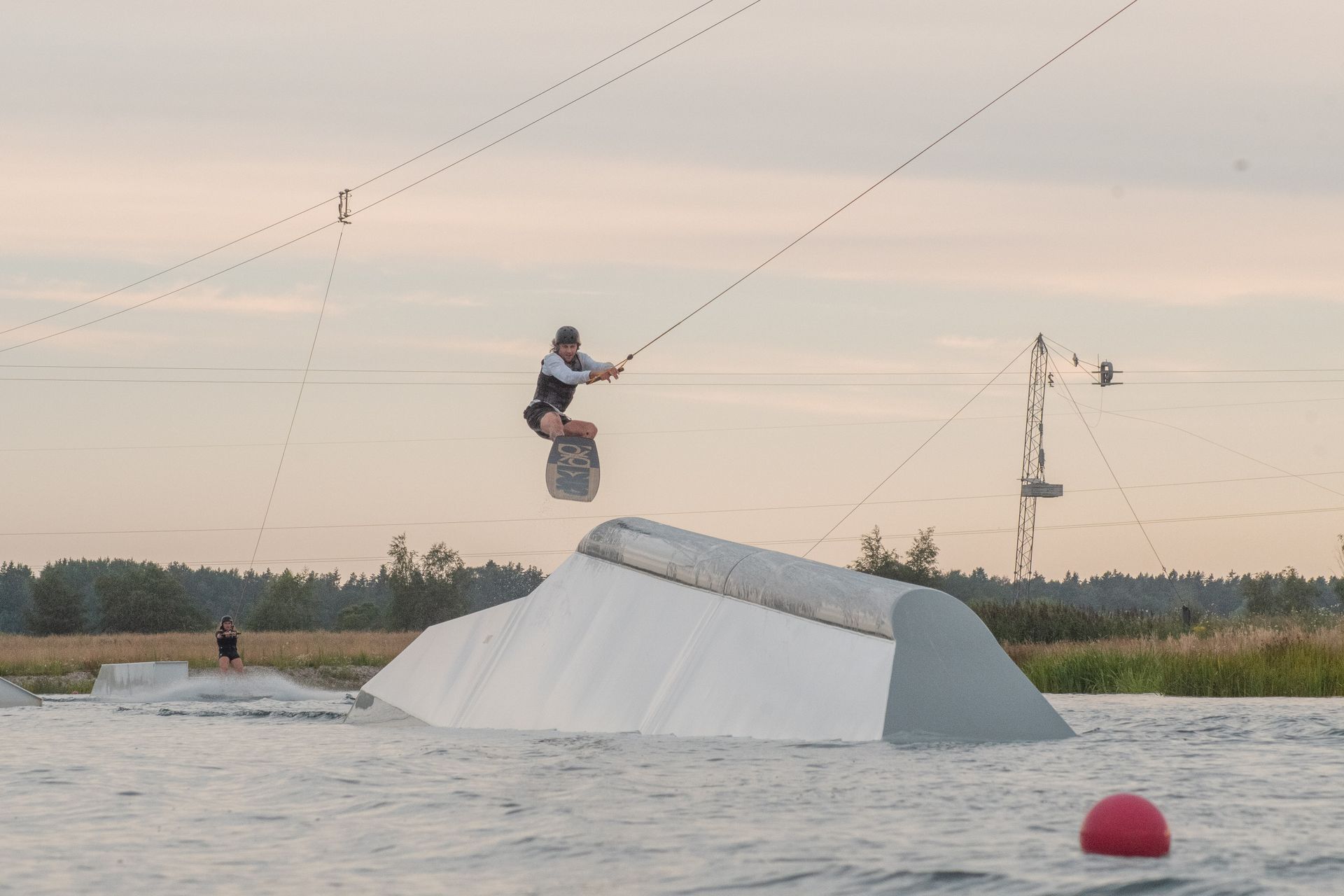 Thrilling wakeboarding jump over ramp at sunset, capturing the essence of water sports adventure.