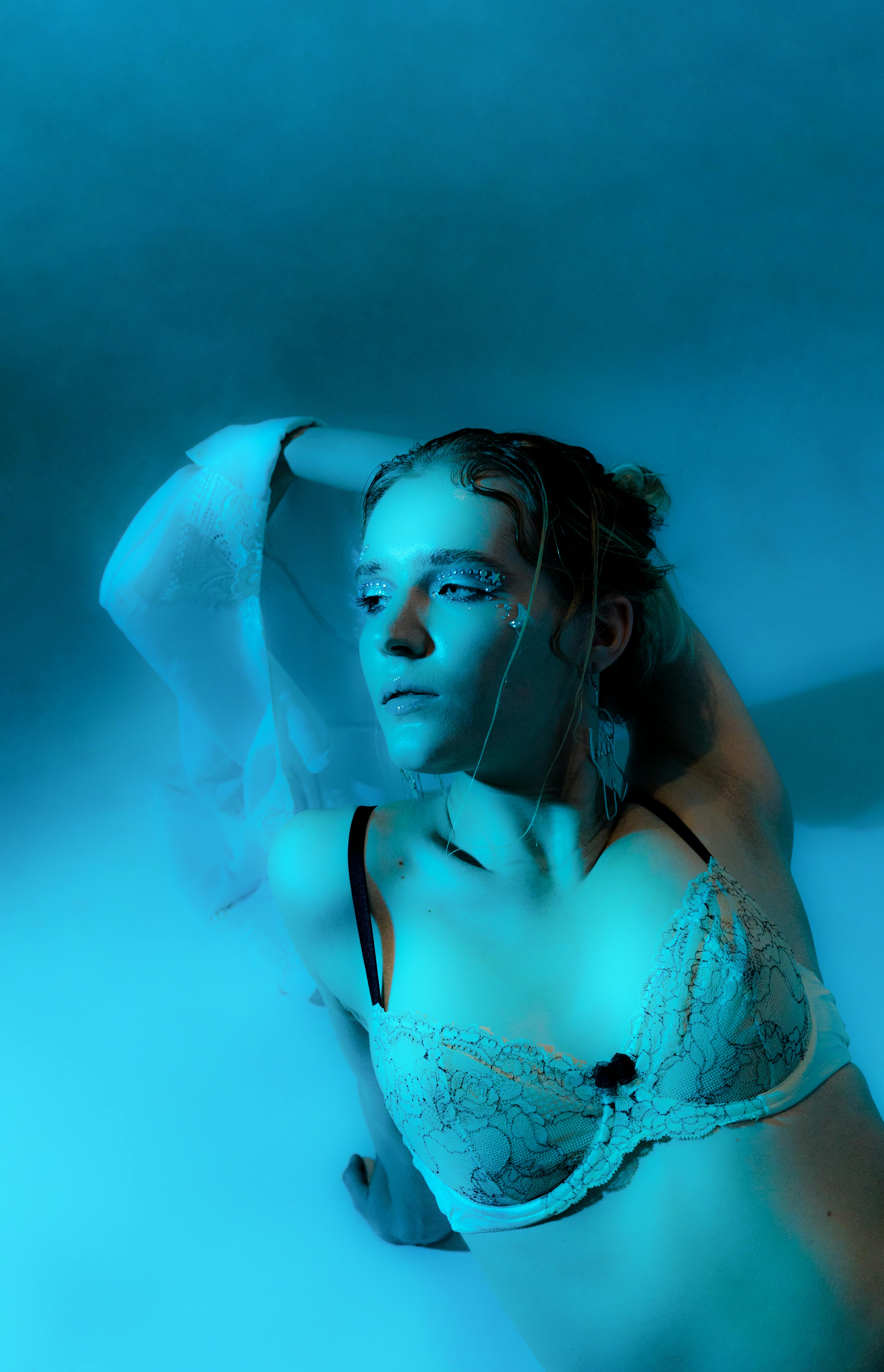 Gorgeous woman in bra sitting on floor in blue lights · Free Stock Photo