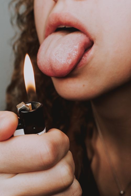 Crop woman with lighter and tongue out · Free Stock Photo